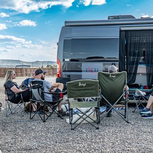 People in camp chairs in front of a van