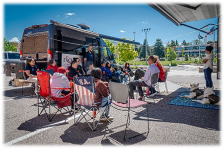 Students listening on chairs in a parking lot